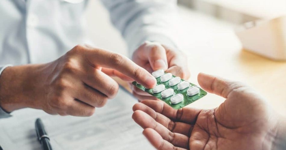 داروساز در حال توضیح روش مصرف یک ورق قرص به بیمار حین انجام فرایند تلفیق دارویی ترخیص